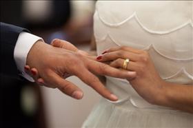 A bride putting a wedding ring on her groom's finger